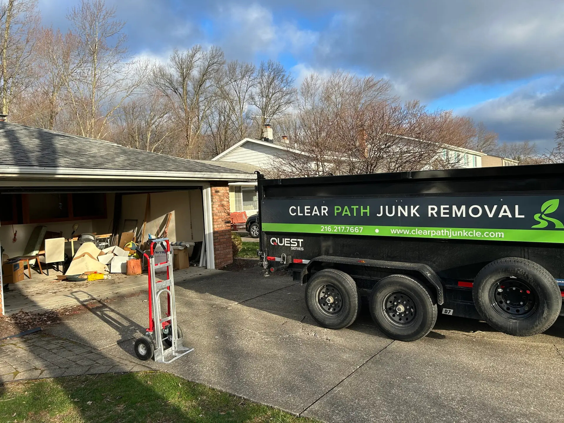 Clear Path Junk Removal dump trailer parked in a residential driveway for a garage cleanout in North Olmsted, OH.